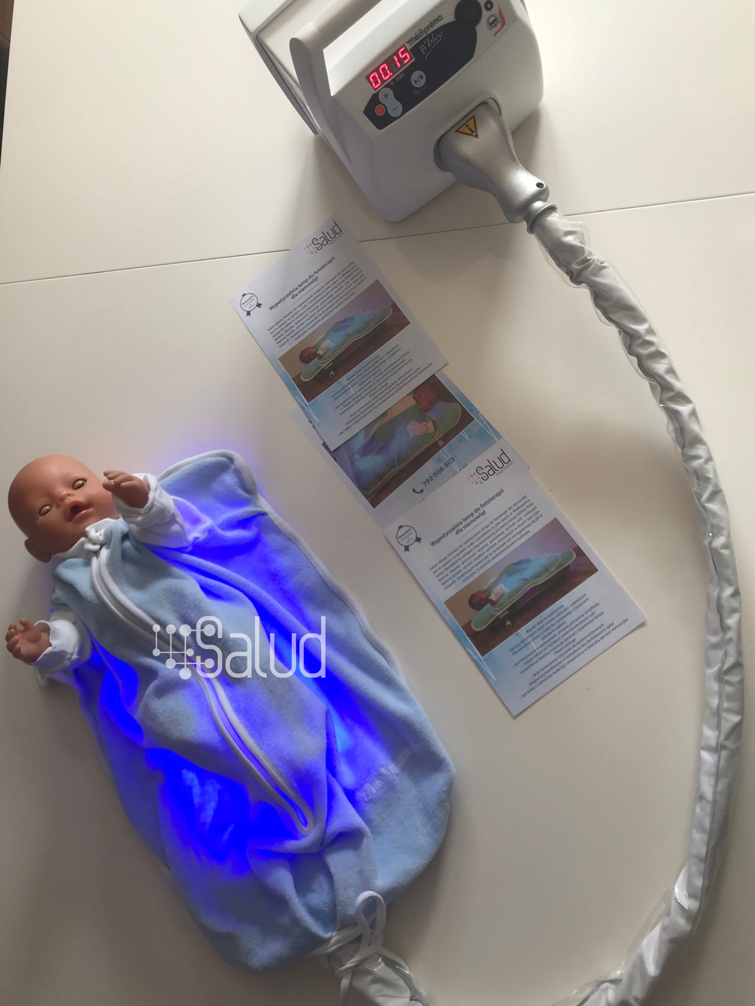 Lalka obrazująca zastosowanie kocyka i lampy do fototerapii